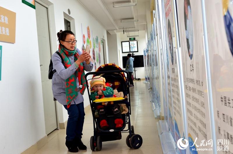一位母親帶著年幼的孩子，在家庭教育基地學(xué)習(xí)后，對宣傳畫板進行拍照。.jpg